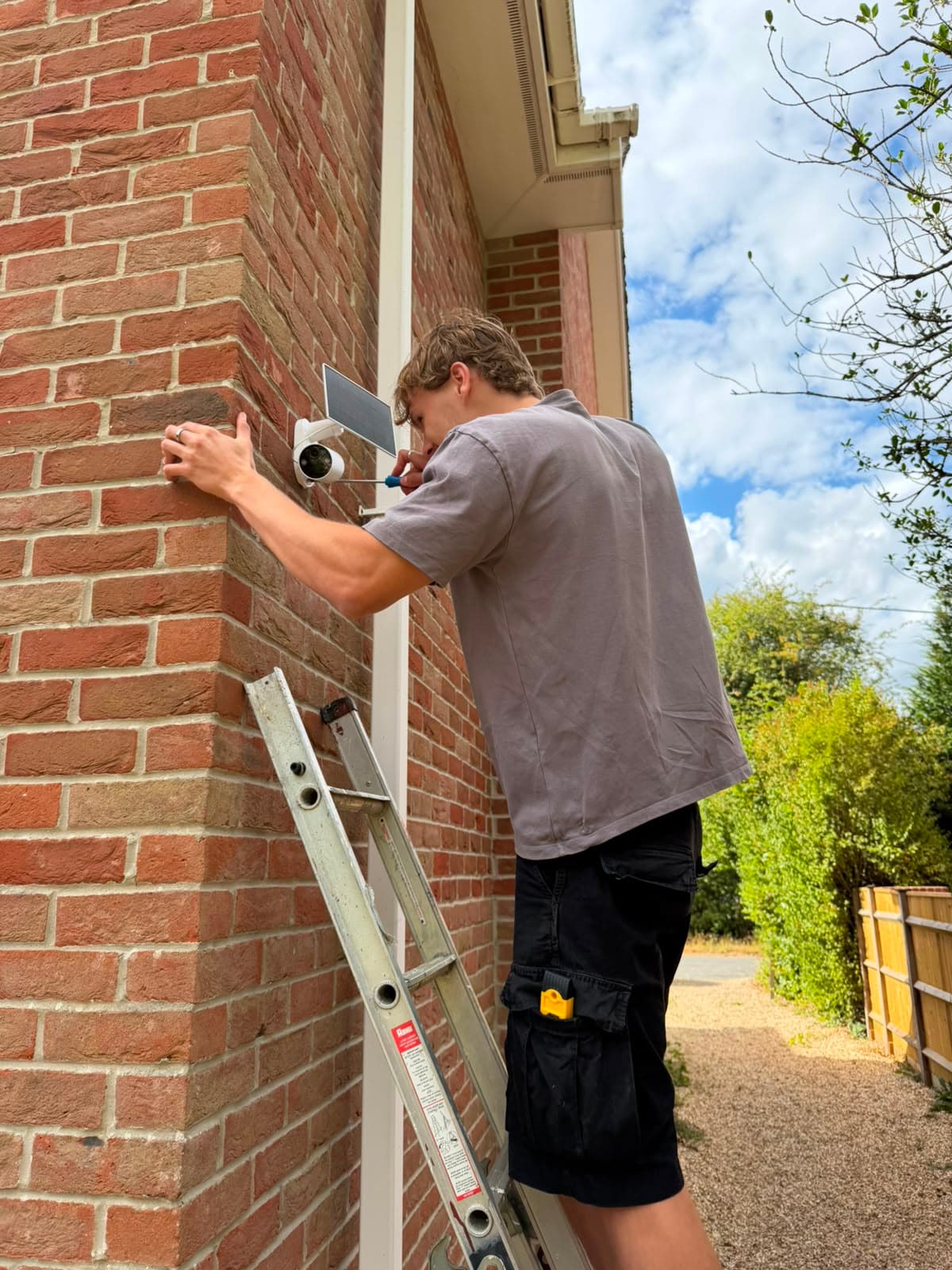 Solar security camera installed on a brick wall corner in natural daylight
