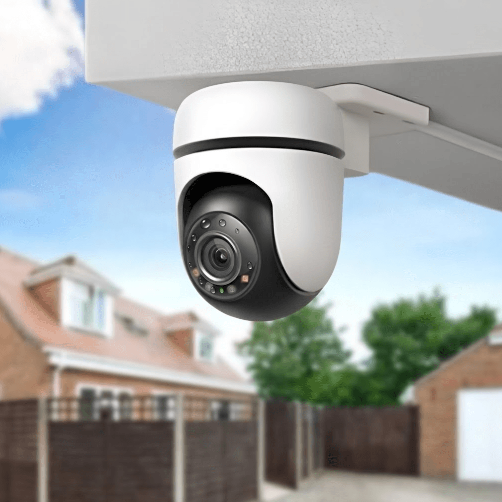 Wired outdoor security camera mounted under a soffit overlooking a residential driveway